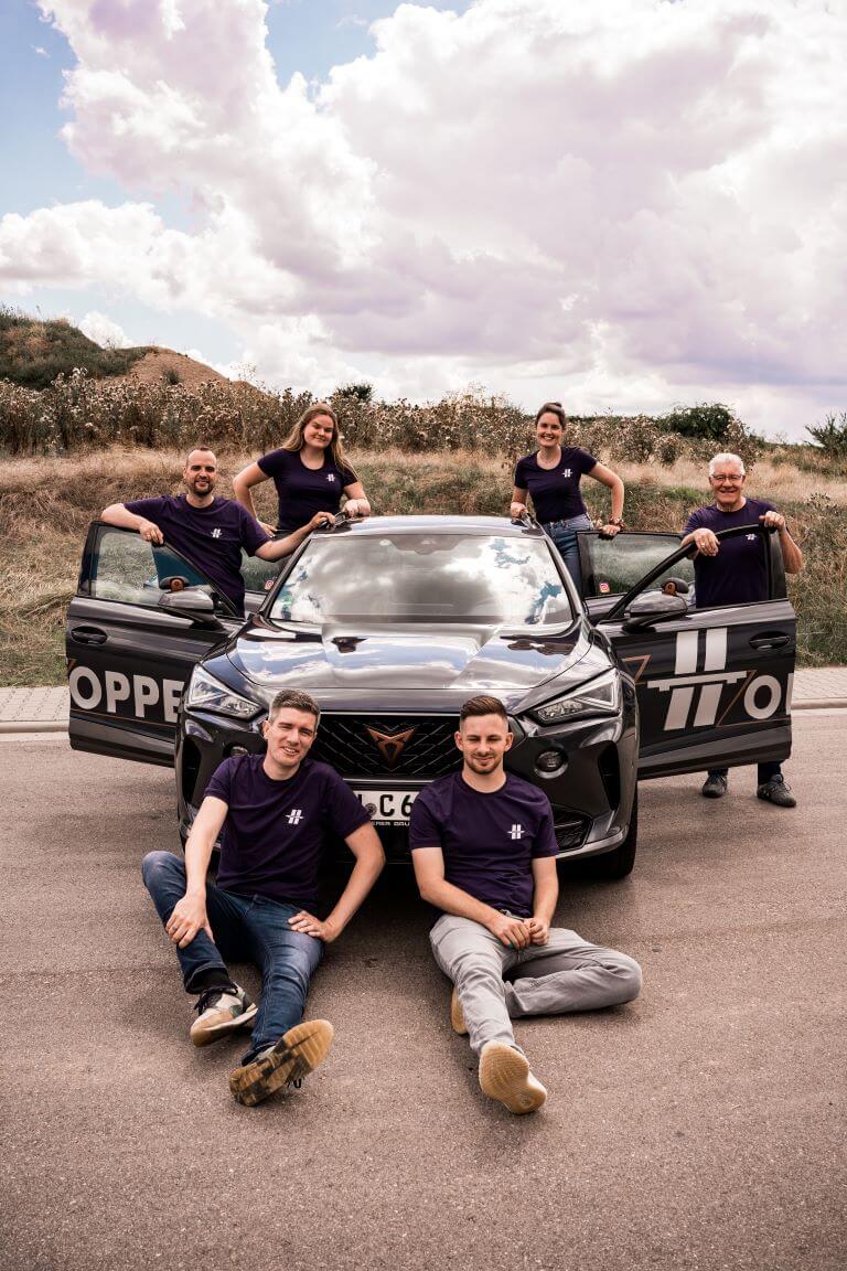 Gruppenbild des kompletten Teams der Fahrschule Hoppe vor einem Fahrschul-Auto