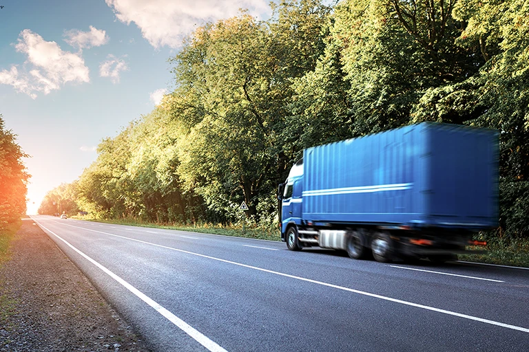 blauer Lkw fährt eine Schnellstraße entlang